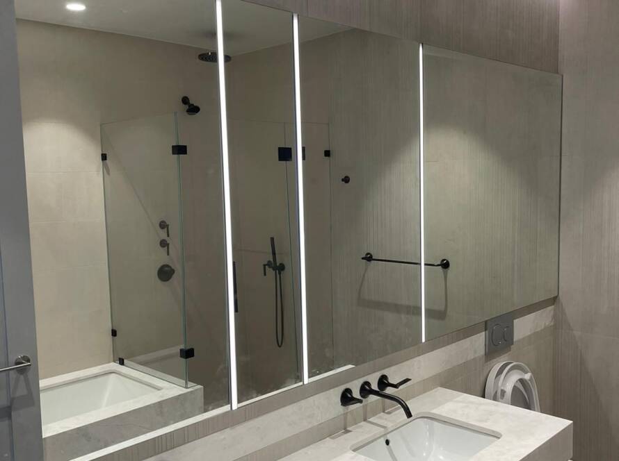 Custom LED backlit bathroom mirror installed over a double vanity in a NYC home